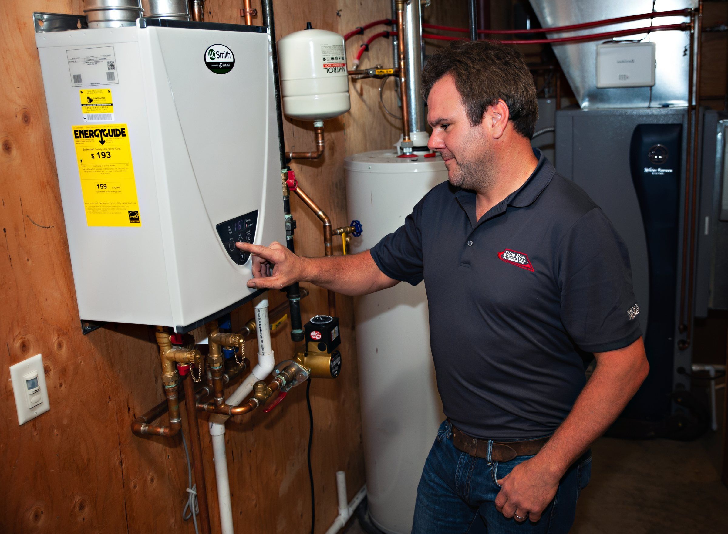 Dick Rich Plumbing technician checking a wall-mounted tankless water heater