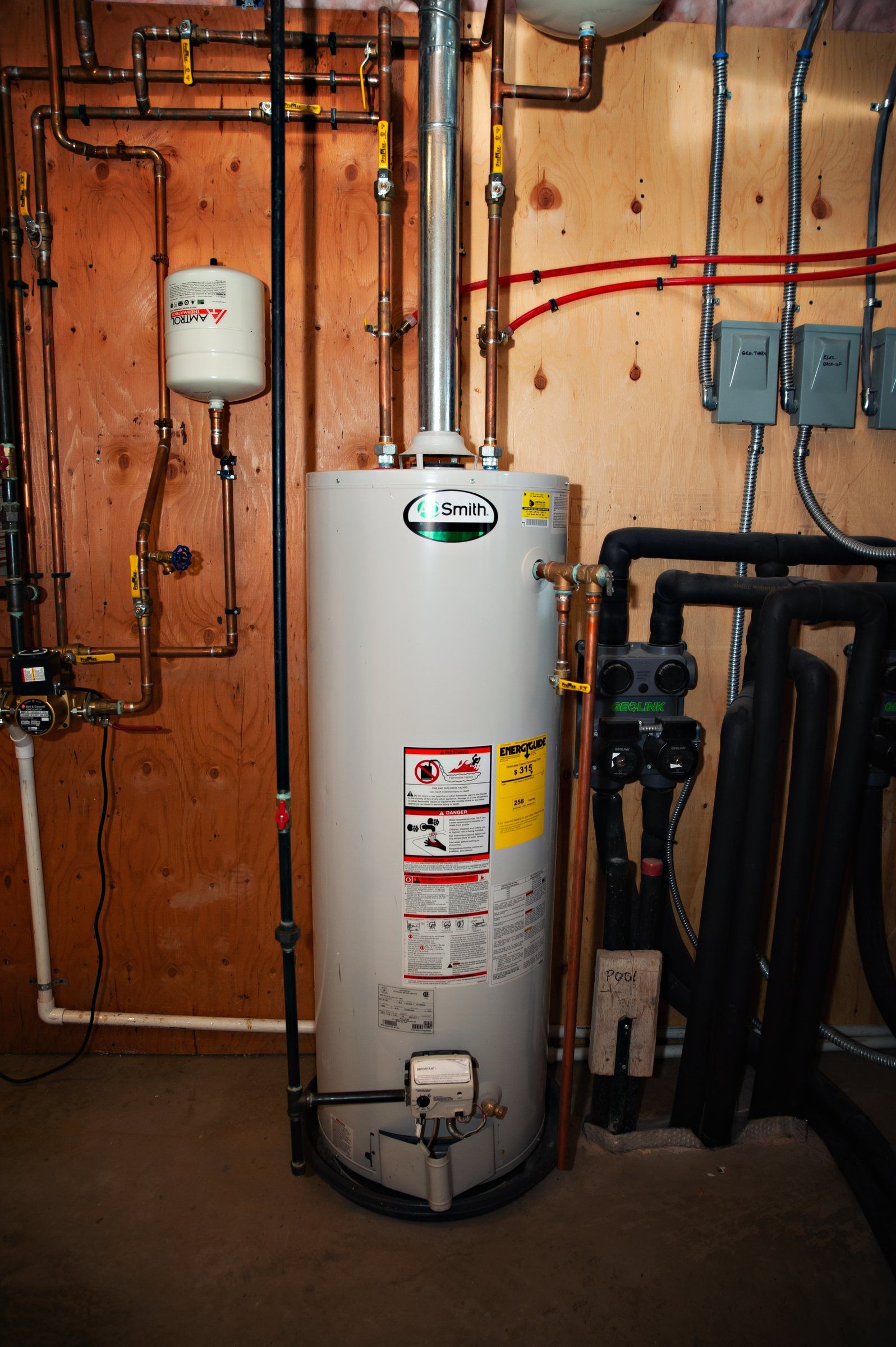 Gas tank water heater installed in a basement mechanical room with PEX supply lines